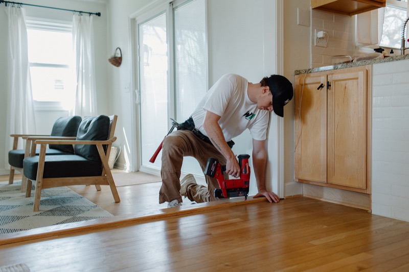 Benny installing a hardwood floor transition with a finish nailer in Kalamazoo, MI