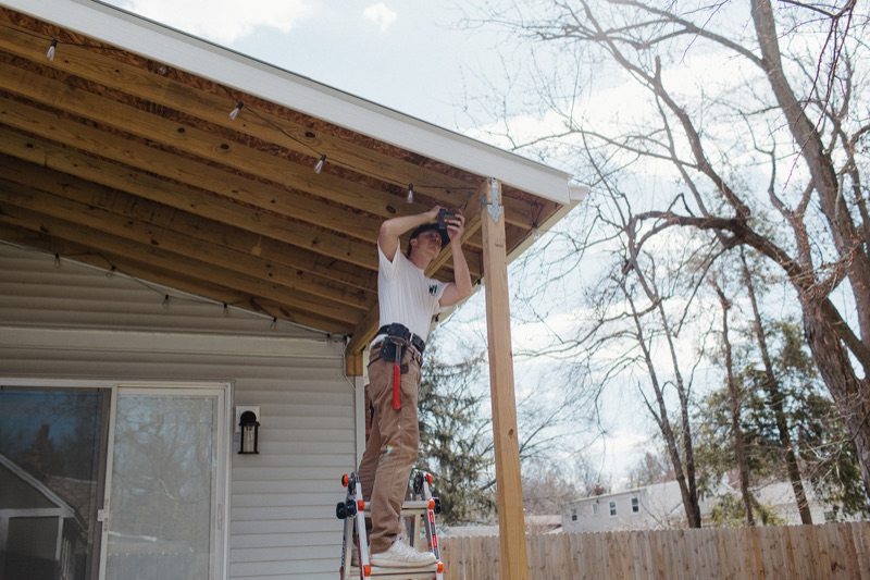 Benny working on porch roof framing from a ladder in Kalamazoo, MI